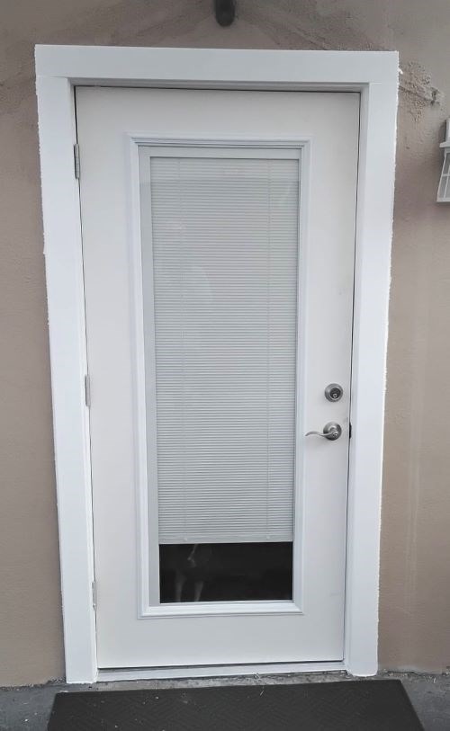 White door with blinds, set in a tan wall, pre-renovation.
