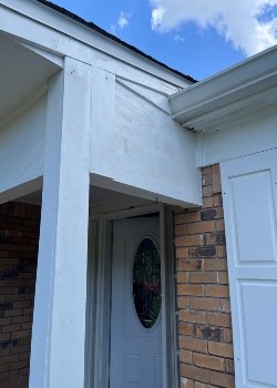 House entrance with white trim and brick wall under blue sky.