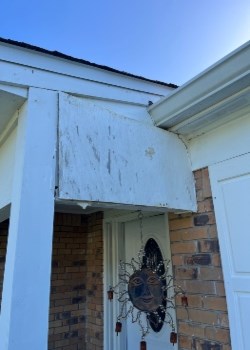 Worn exterior house paneling with sun decoration hanging.