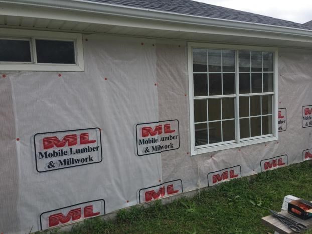 House exterior with construction wrap and framed windows.