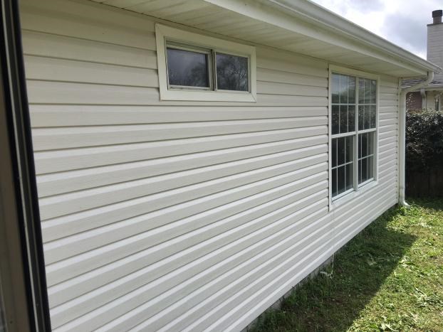 House with white siding and windows, grass in foreground.