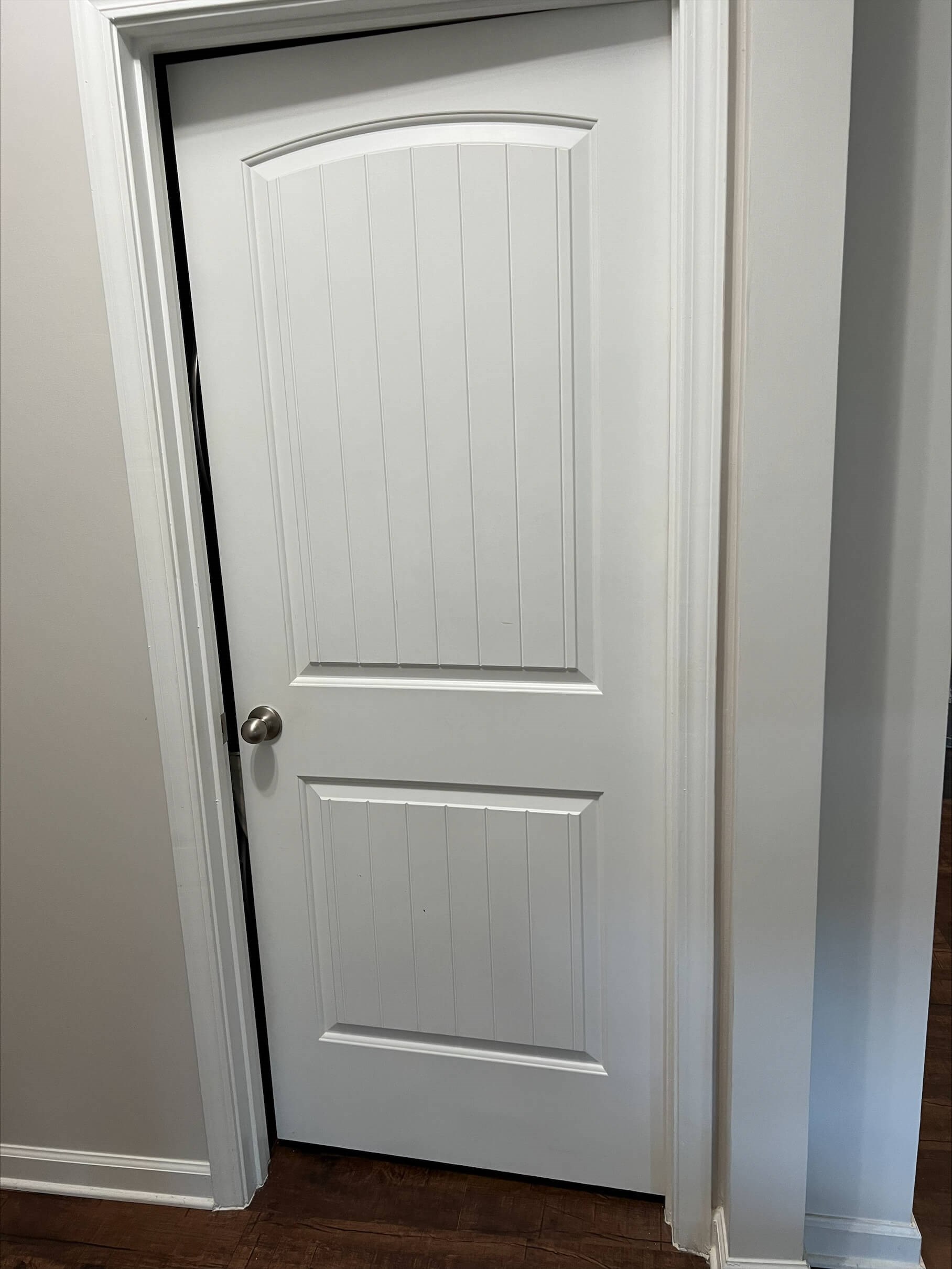White interior door slightly ajar in a hallway.