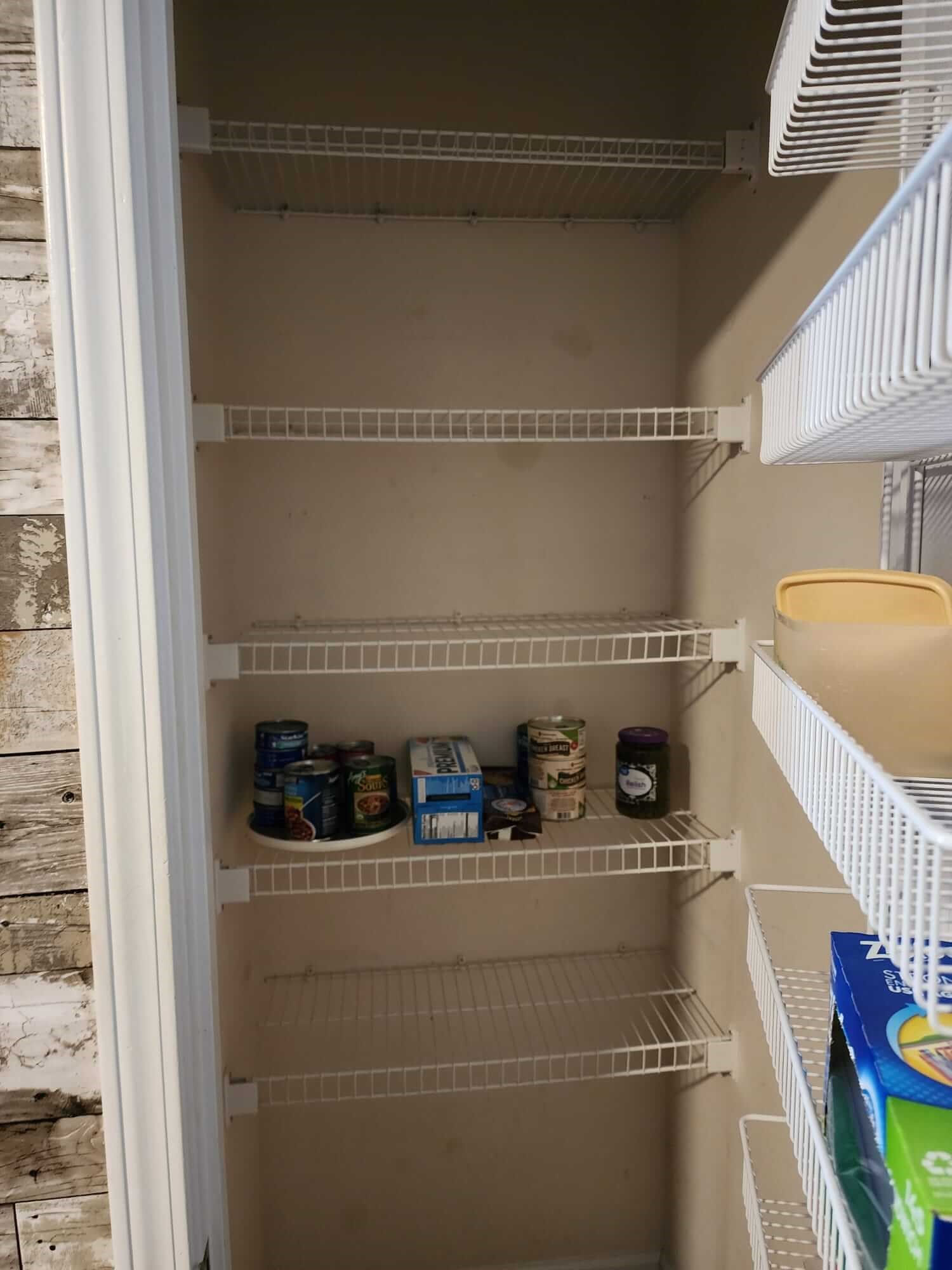 Empty pantry with wire shelves, a few cans and boxes.