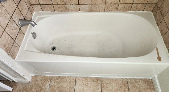 Refinished bathtub with surrounding tile walls and floor.