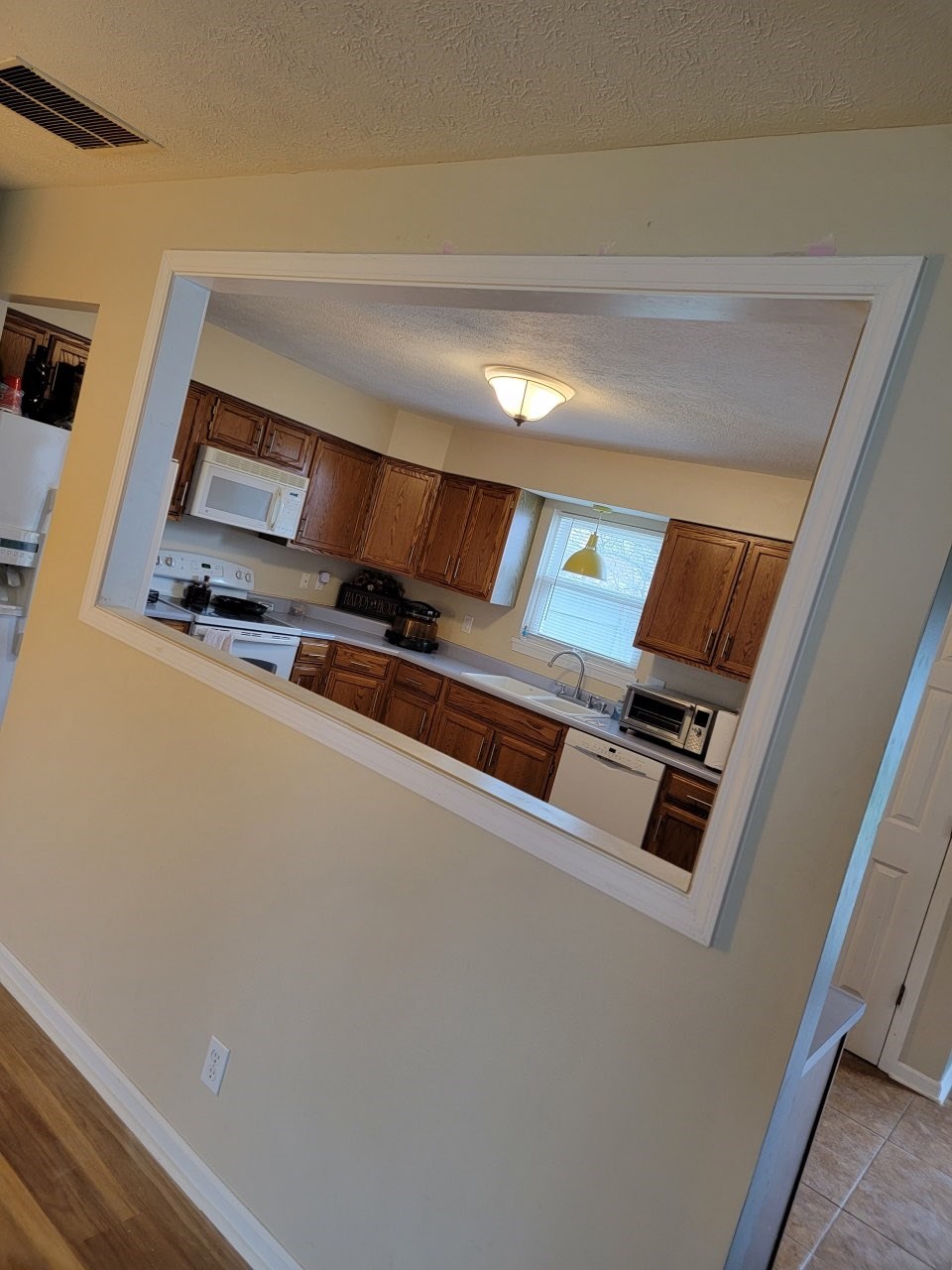 Wall opening to kitchen with wooden cabinets and appliances.