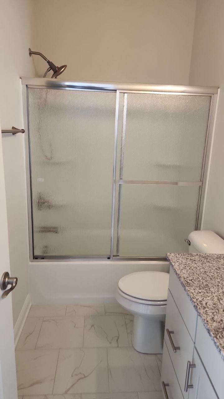 Bathroom with shower, toilet, and granite countertop.