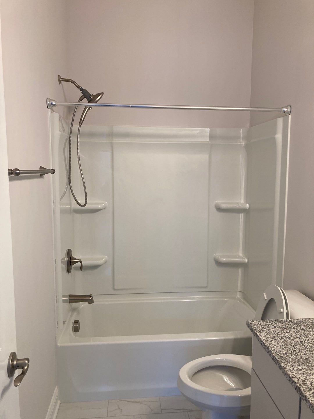 Bathroom with tub, toilet, and granite countertop.