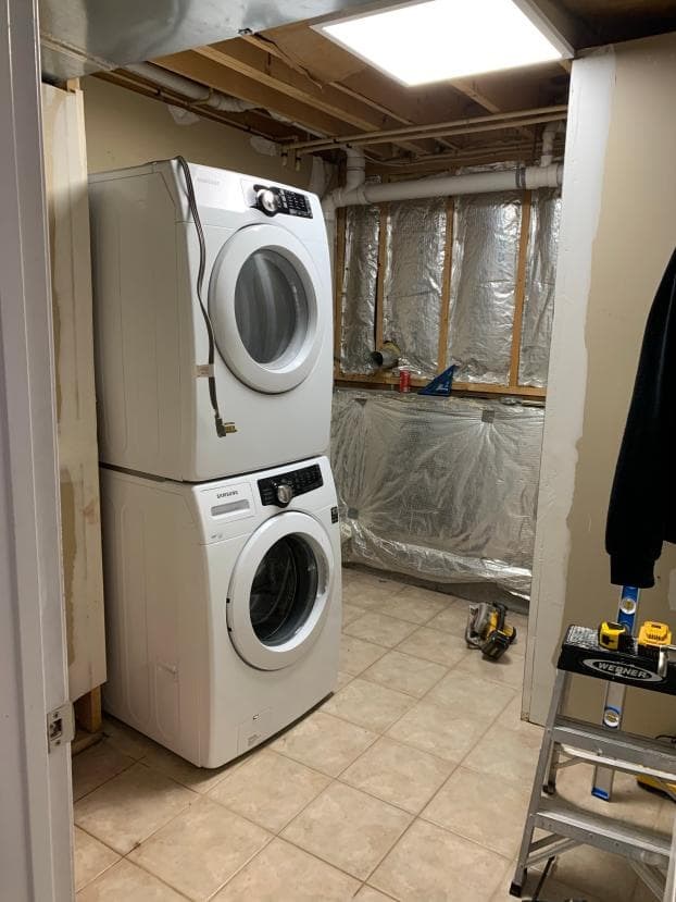 Unfinished laundry room with stacked washer and dryer.