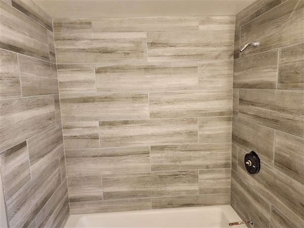 Bathroom shower with new wood-patterned tile installation.