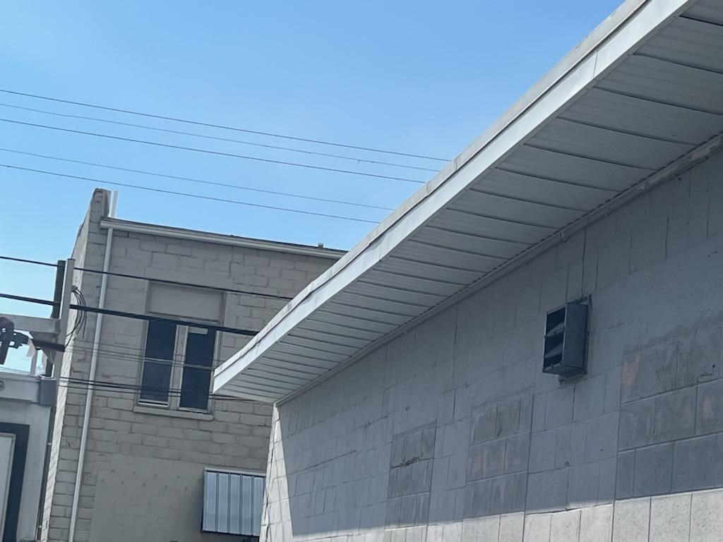 Side view of a building with a gray exterior and white roof.