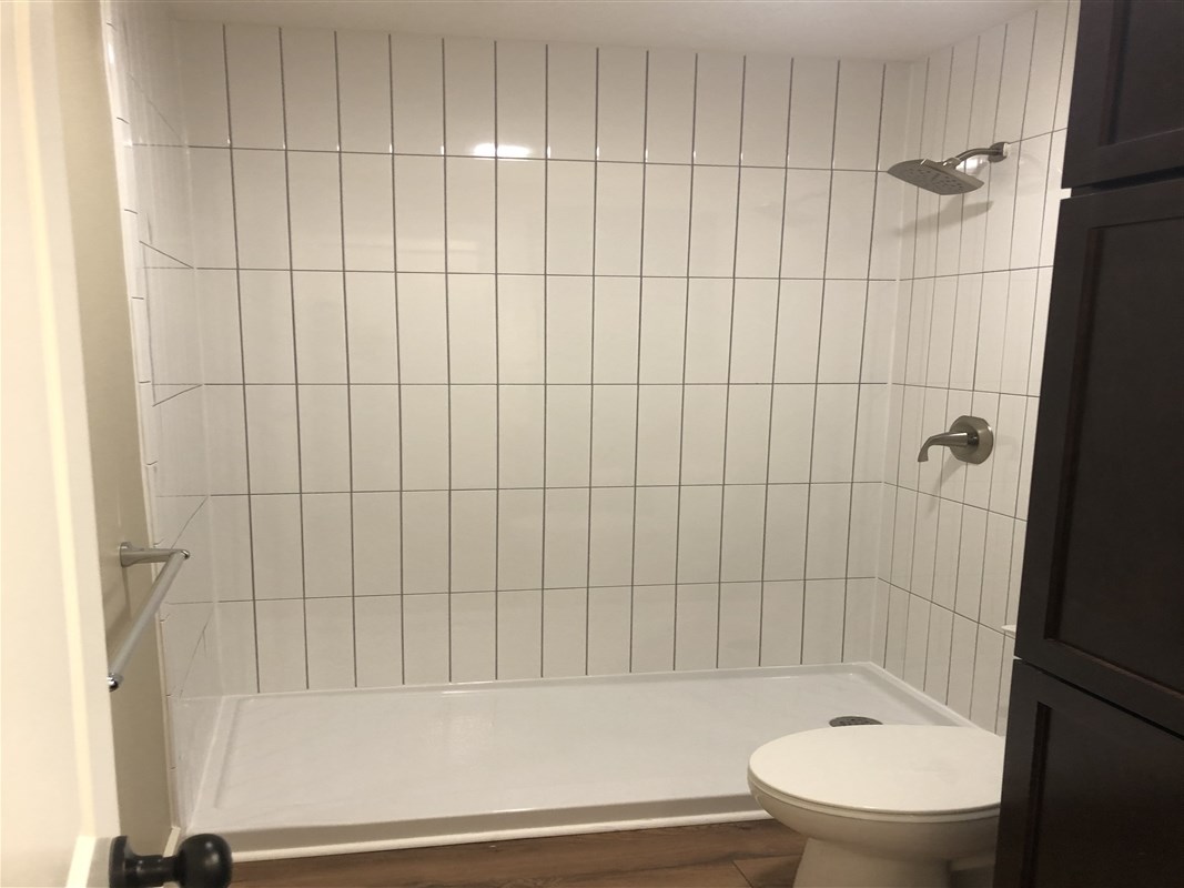 Bathroom with tiled shower and wooden floor.