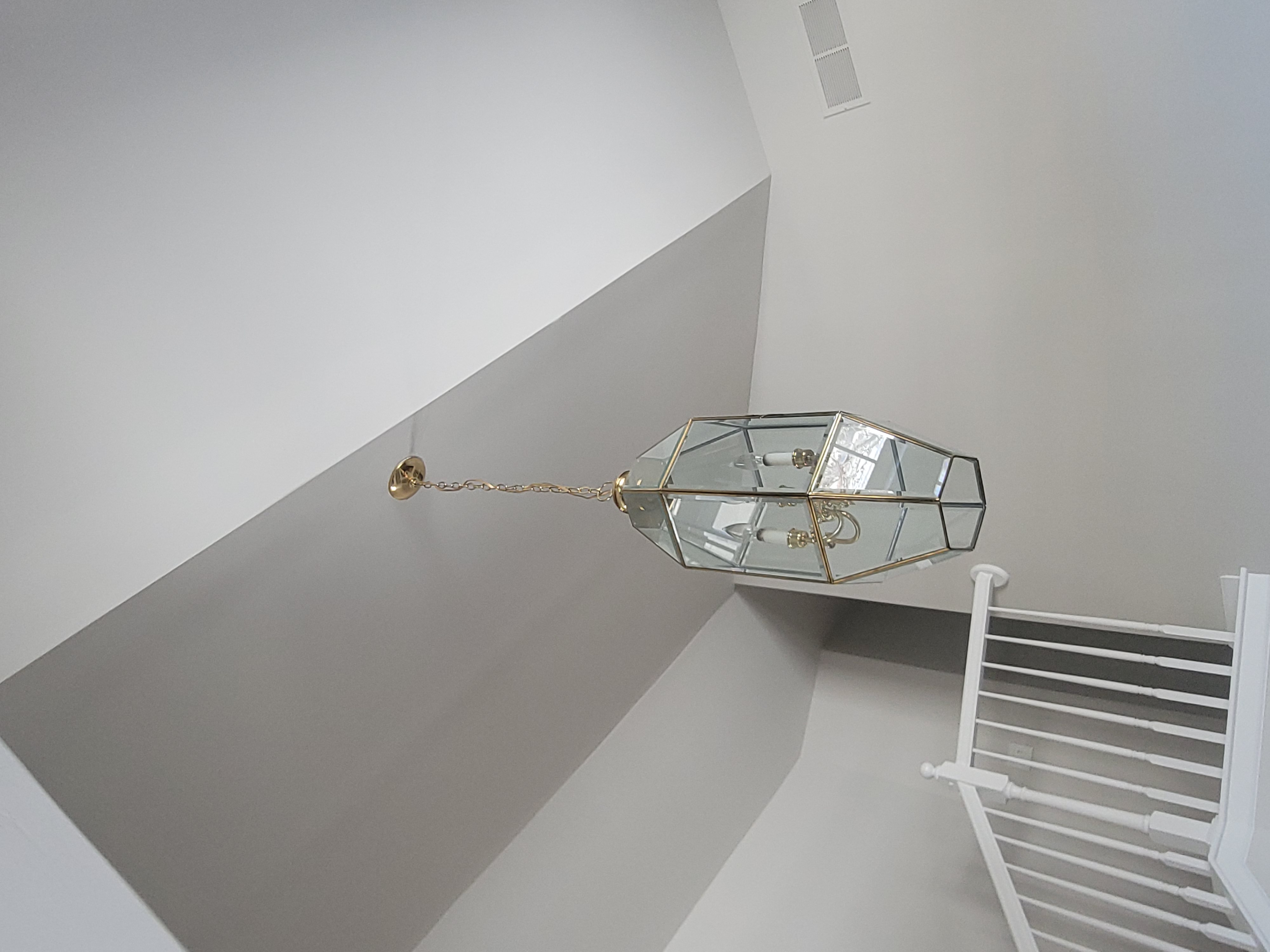 Hanging glass chandelier near staircase ceiling area.