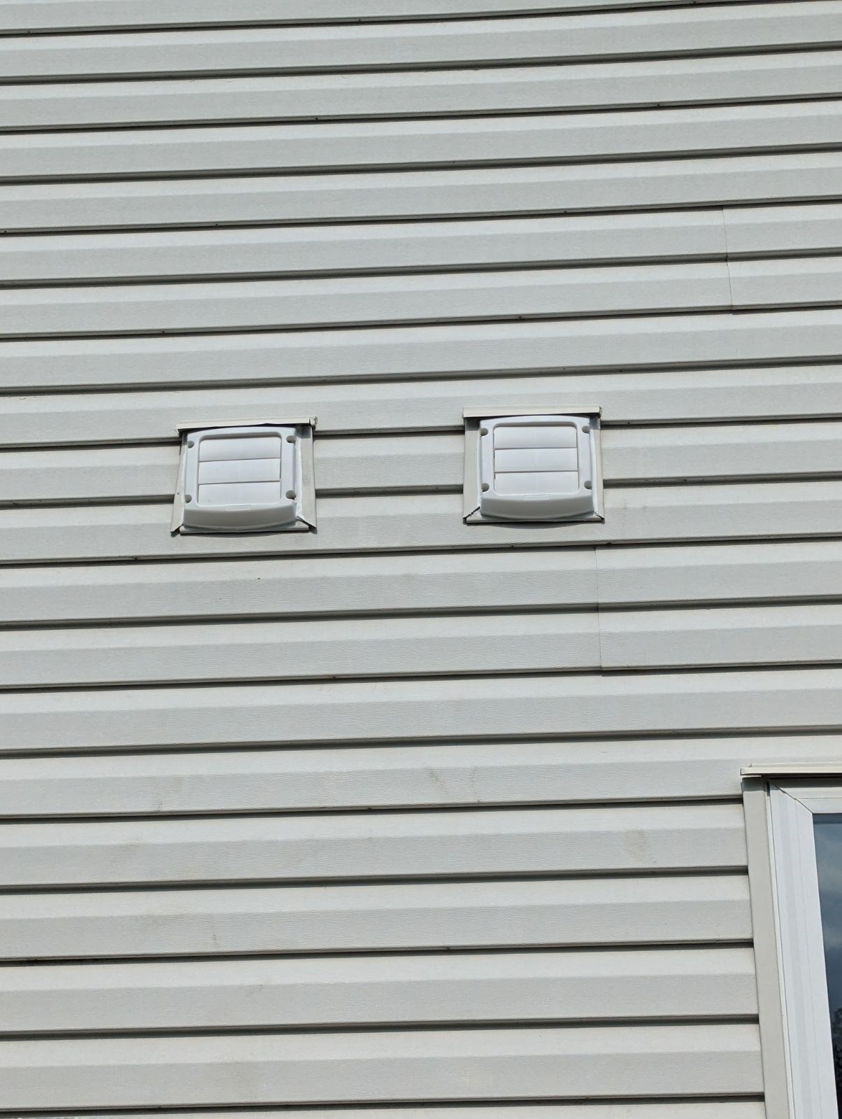 House exterior with two vent covers on the siding.