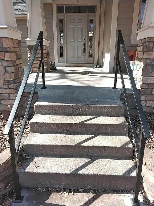 Concrete steps with new black metal railings installed.