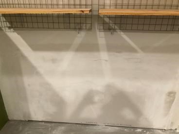 Wall with shelves and wire grid in a handyman project setting.