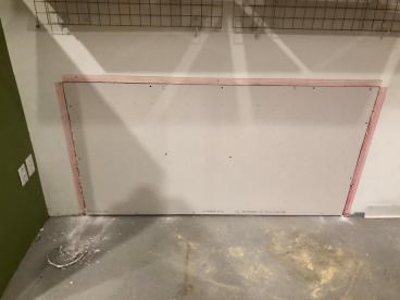 Drywall patch installed in wall with red outline, wires above.