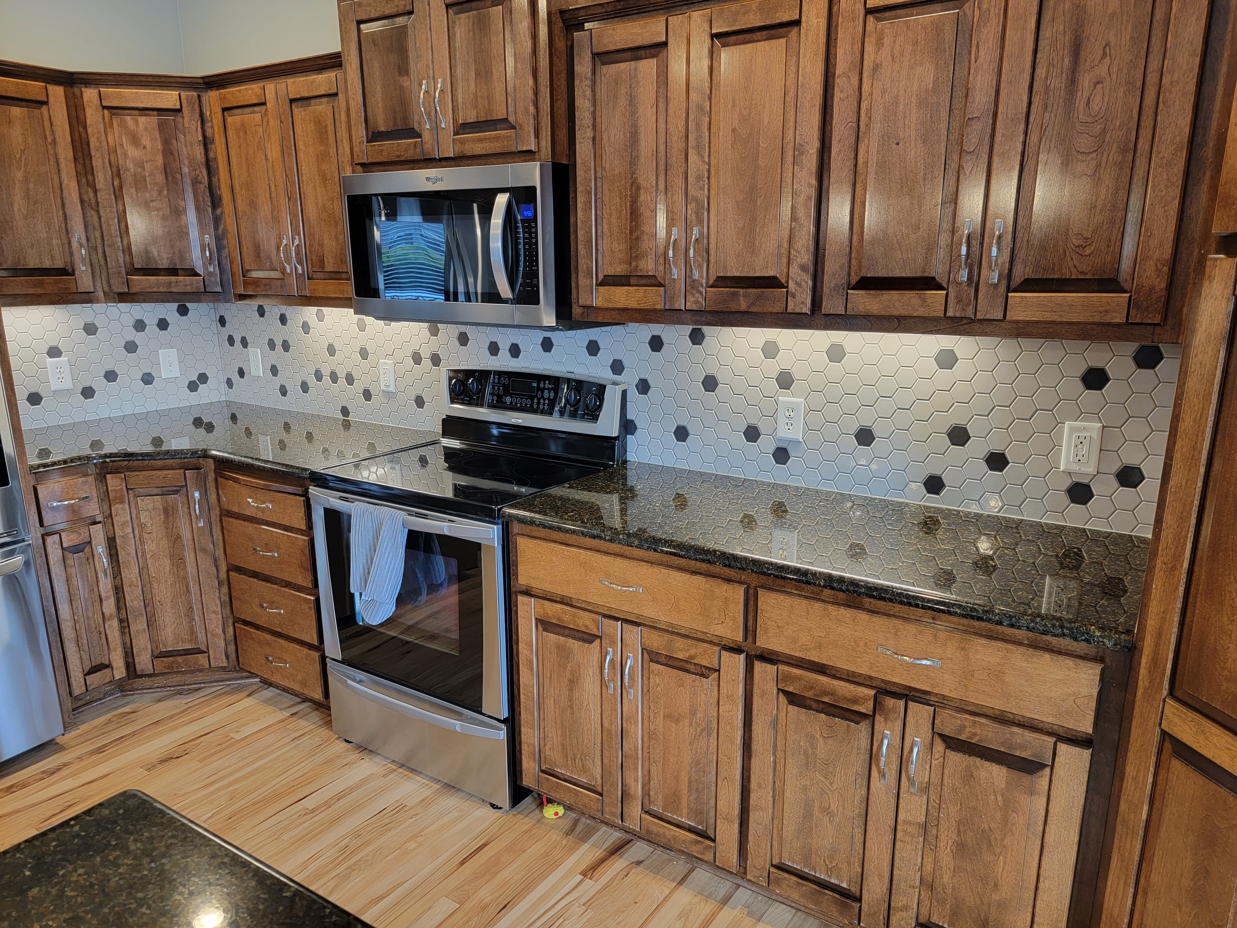 Kitchen with wooden cabinets and hexagonal tile backsplash.