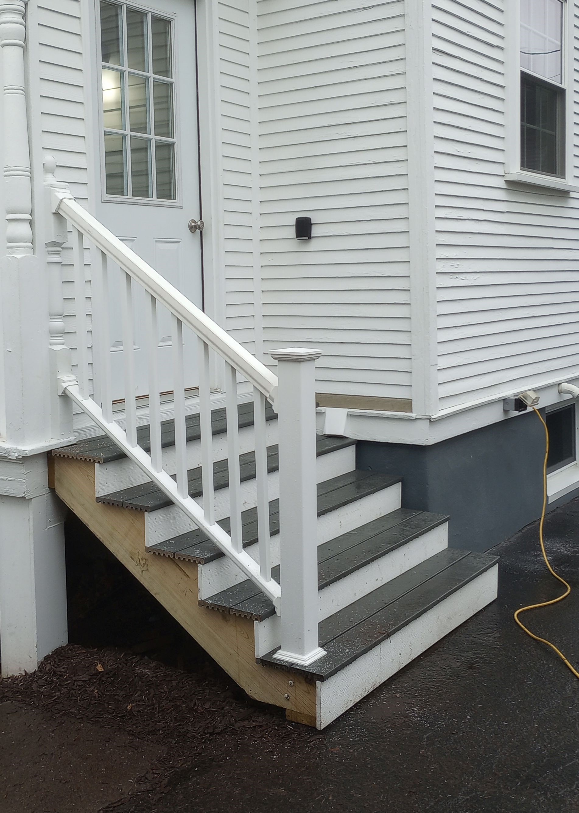 Newly built white porch steps and railing by a side door.