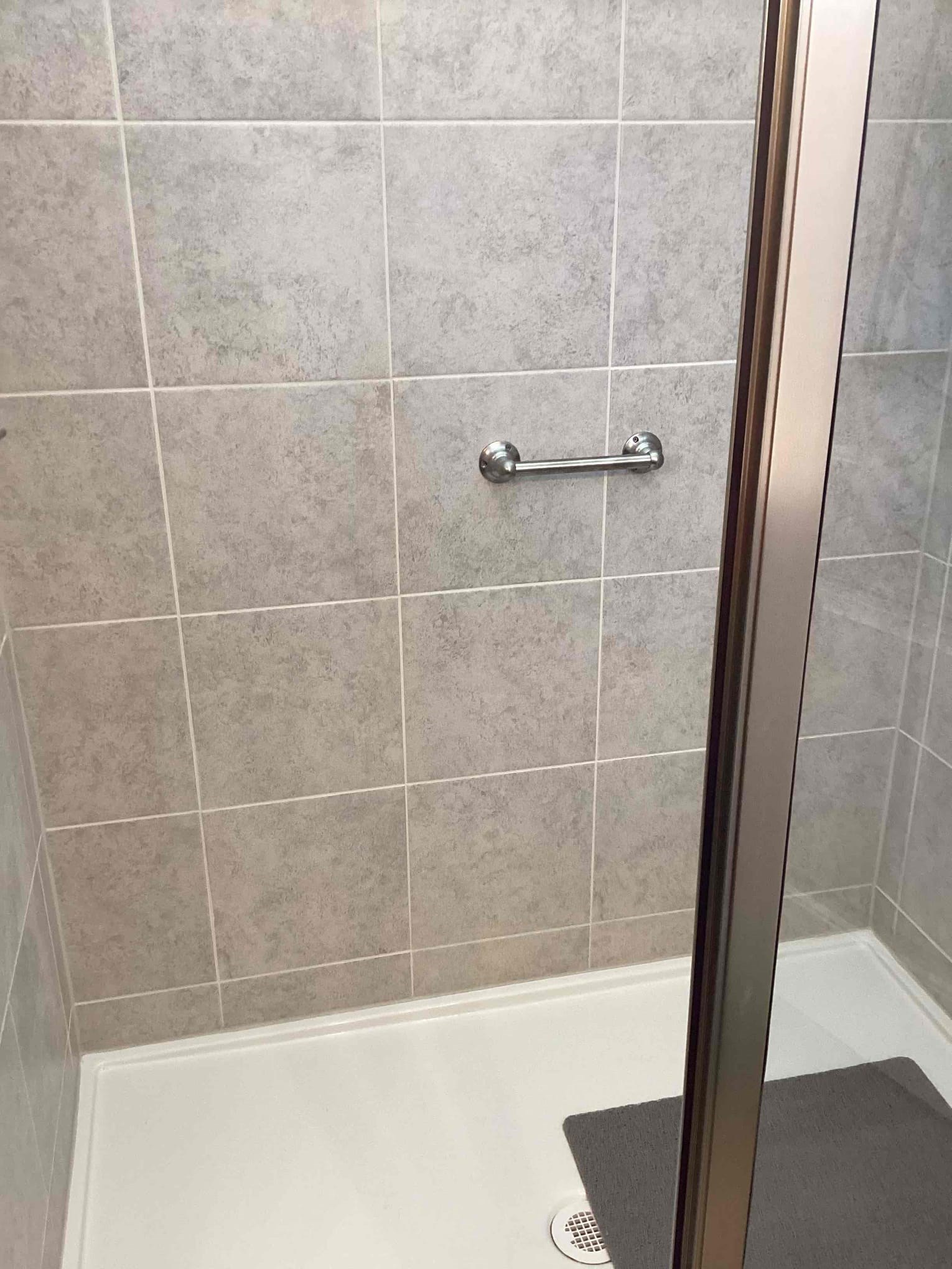 Grab bar installed in a tile shower with a glass door in Clayton NC