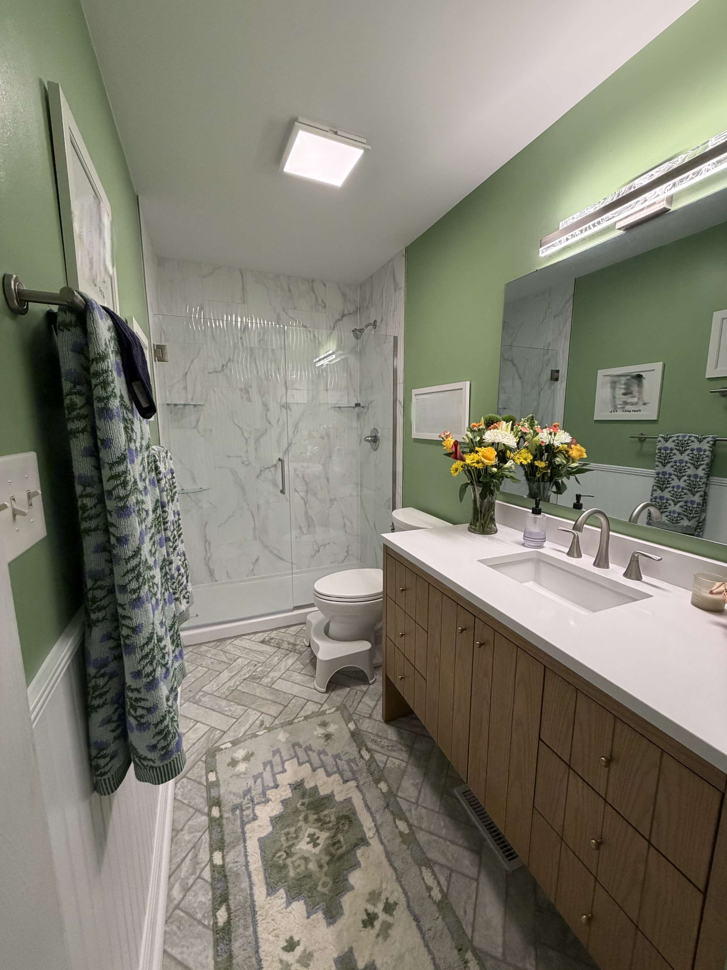 https://acehandyman-dss.ingeniuxondemand.com/Images/Offices/North Carolina/Clayton/41830298-bathroom-remodel-garner-27529-nc-afterv2.jpg Full bathroom remodel in Garner NC with marble-look shower, glass door, wood vanity, wainscoting with chair rail and herringbone tile floor