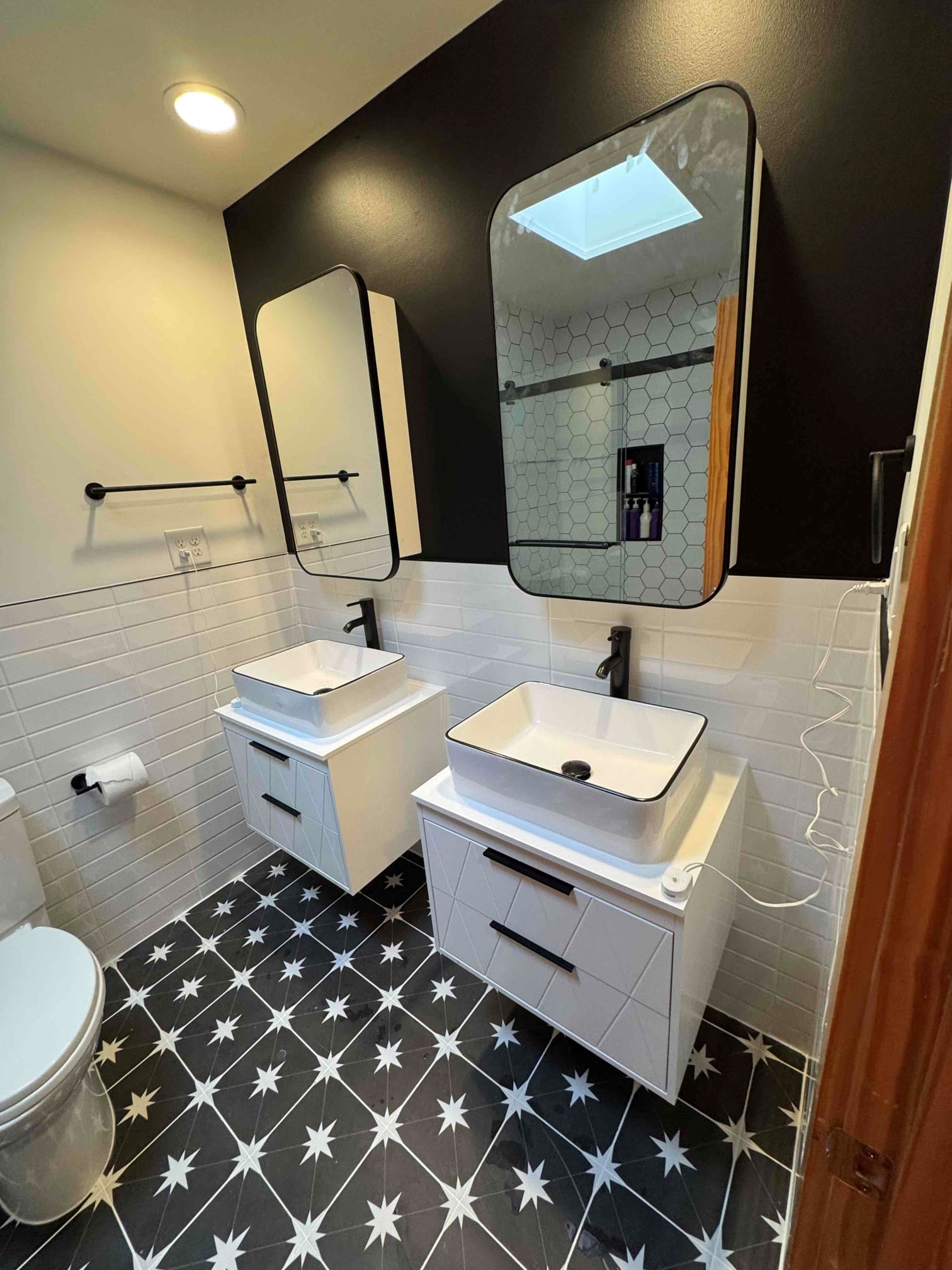 Bathroom remodel completed in Durham NC — dual vessel sinks, black accent wall, and star-pattern tile by Ace Handyman Services