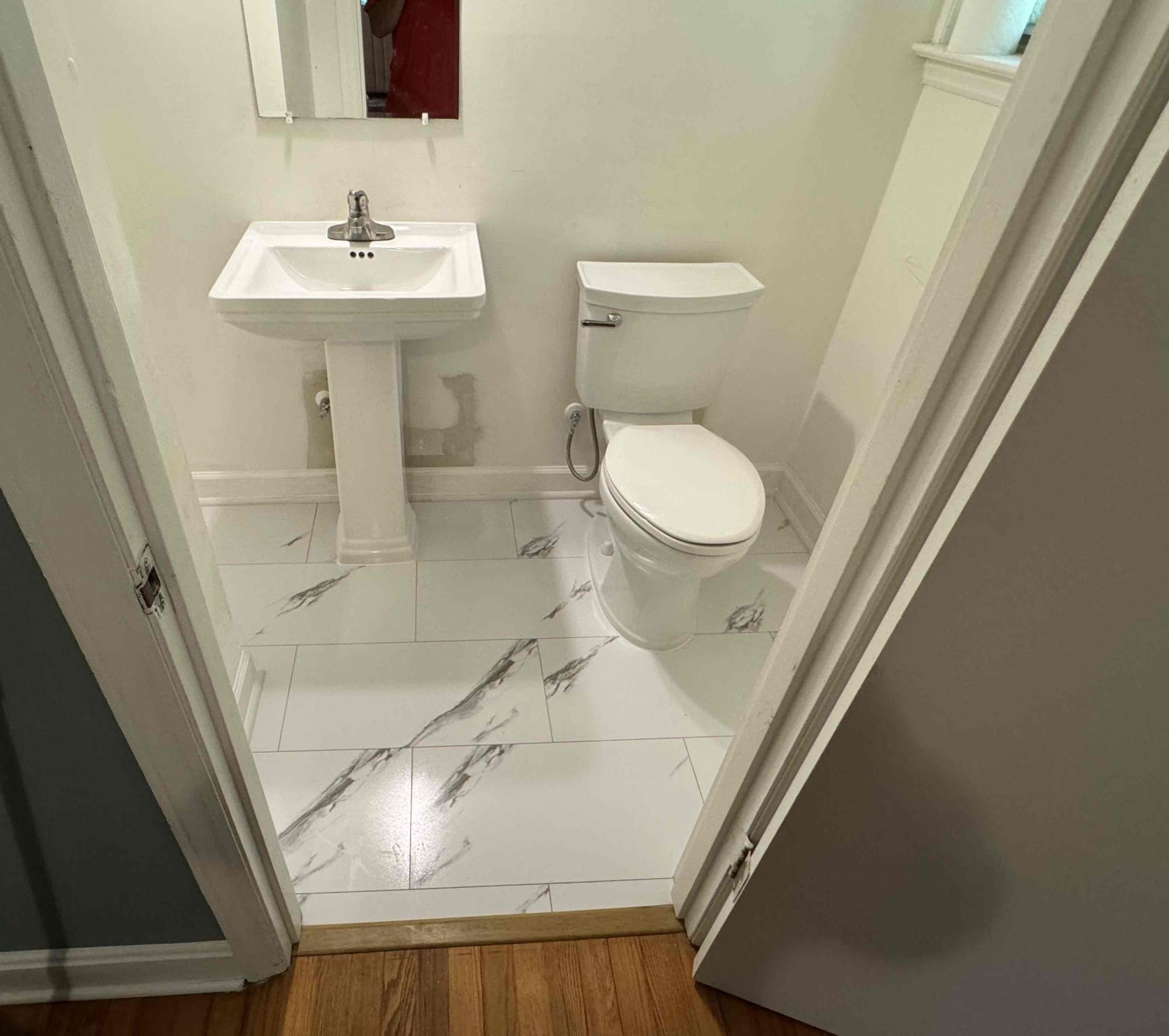 Diagonal marble-look tile floor in a renovated Durham bathroom with pedestal sink