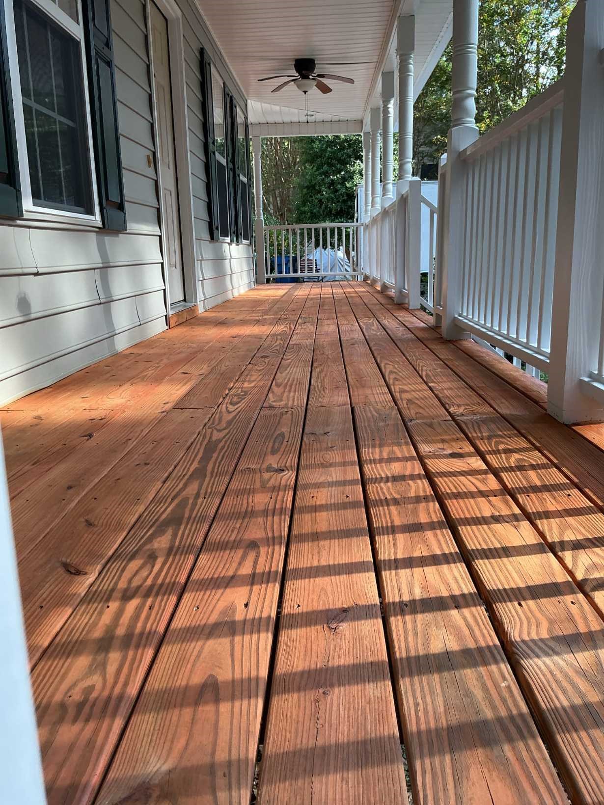 https://acehandyman-dss.ingeniuxondemand.com/Images/Offices/North Carolina/Durham Chapel Hill/32587820-deck-refinishing-stained-covered-porch-after-south-durham-nc-ace-handyman-services.jpg Newly refinished covered porch deck with rich brown stain, white spindle railings, and ceiling fan at a South Durham, NC home by Ace Handyman Services