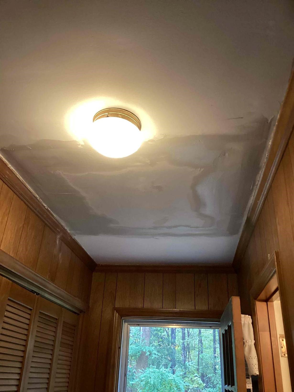 Smoothly repaired and finished ceiling drywall around a brass light fixture in a West Durham, NC home by Ace Handyman Services