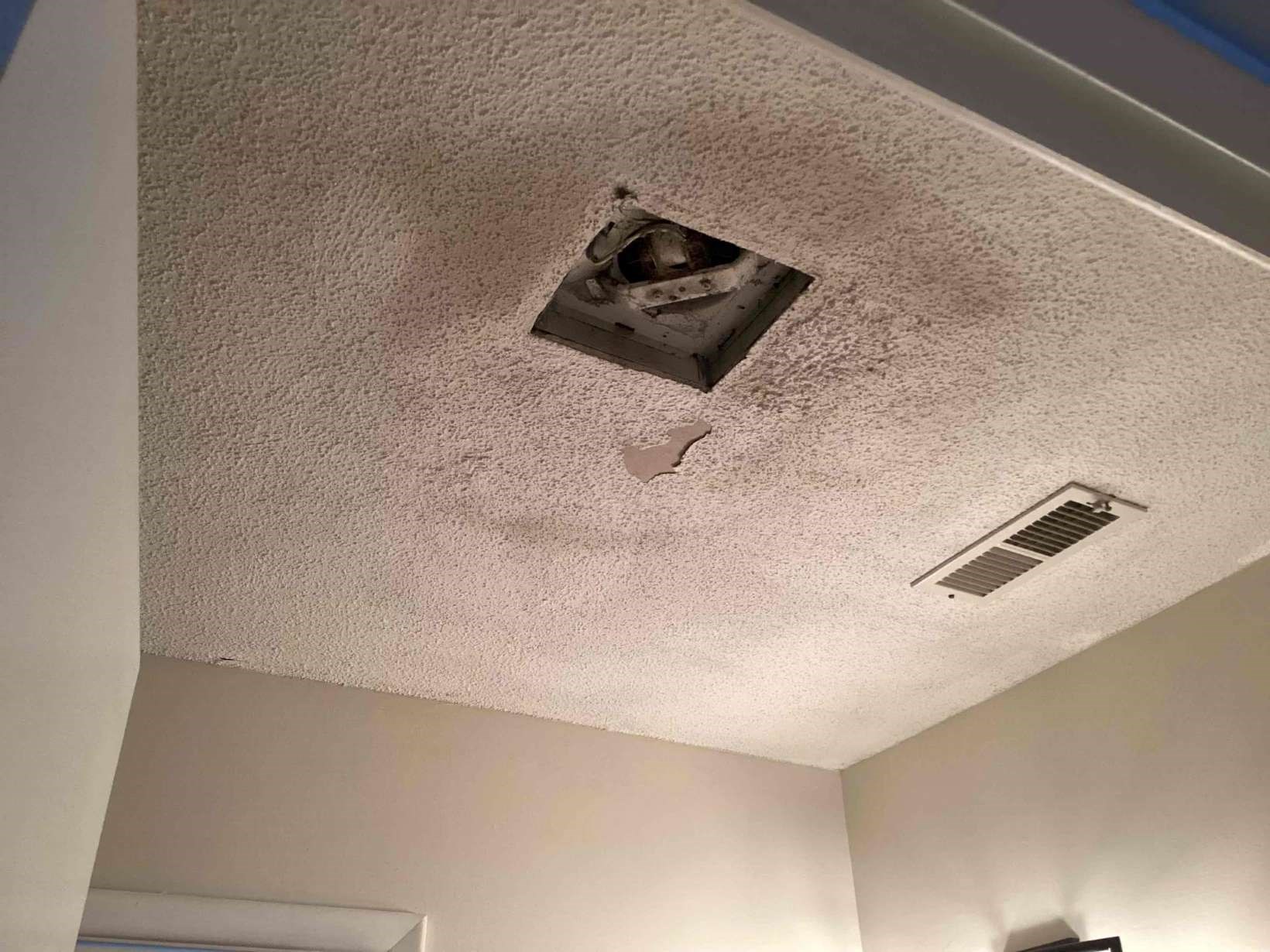 Damaged popcorn ceiling around an exposed bath vent fan housing in a Southwest Durham, NC home before drywall repair by Ace Handyman Services