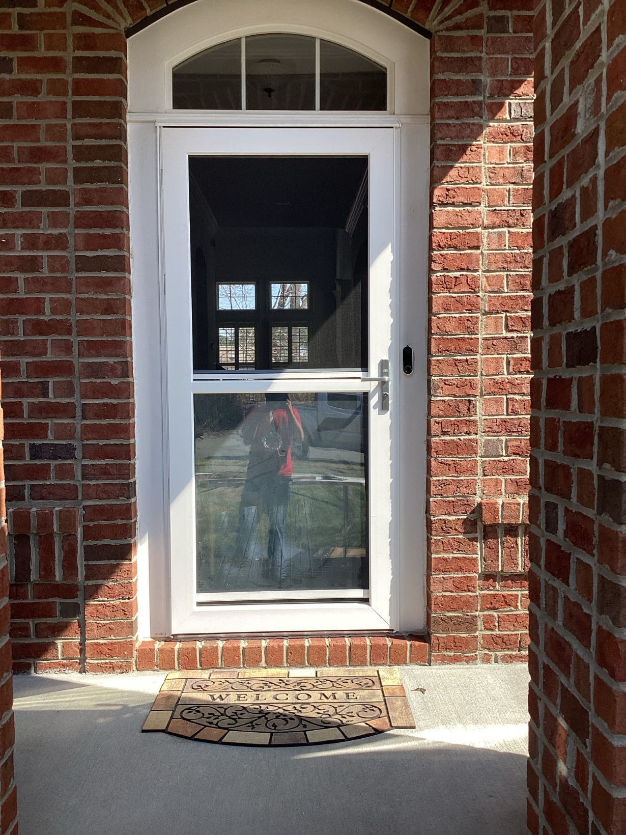 New white storm door installed in the brick front entry of a Durham home