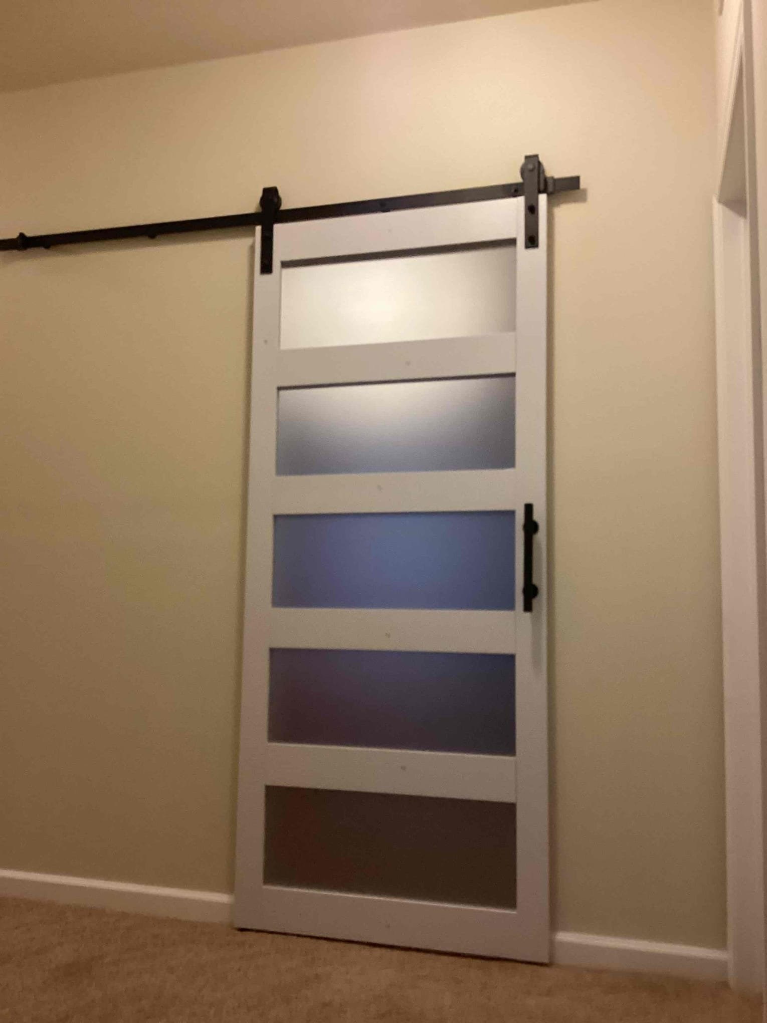 White sliding barn door with black rail hardware installed in a Durham home