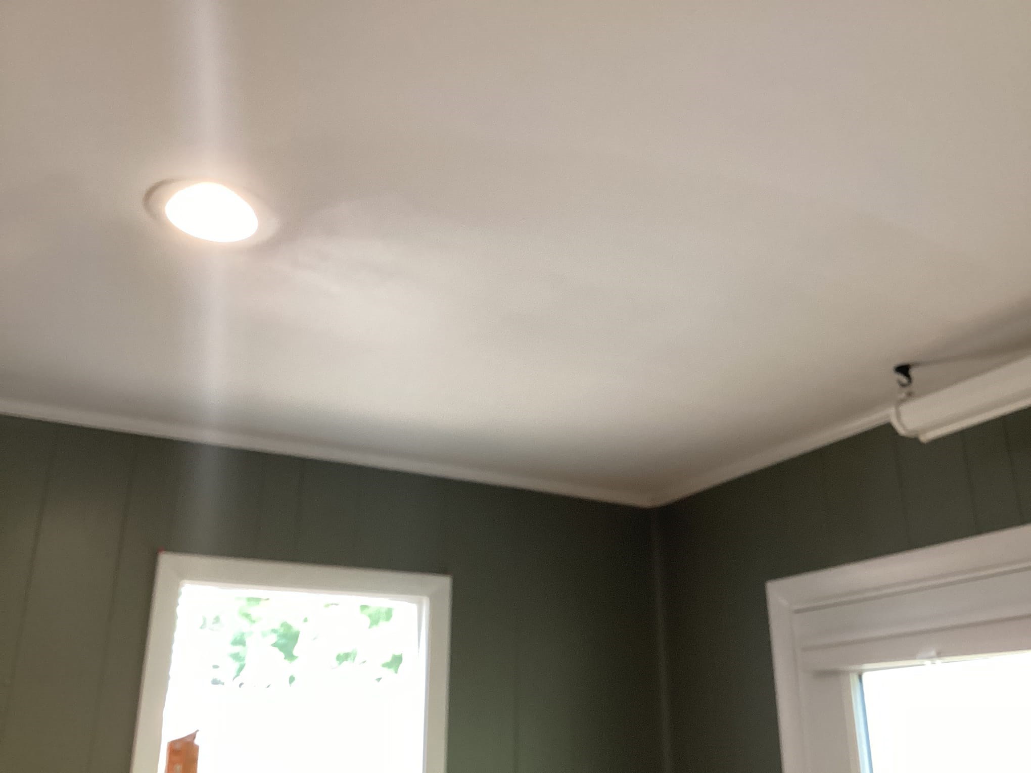 Ceiling with recessed light and green walls in a finished room.