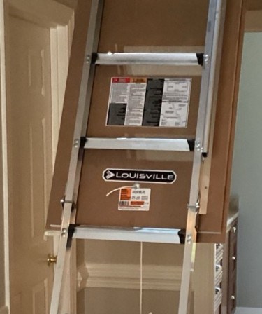 Inside of a Louisville pull-down attic ladder door showing the brand logo and model number label