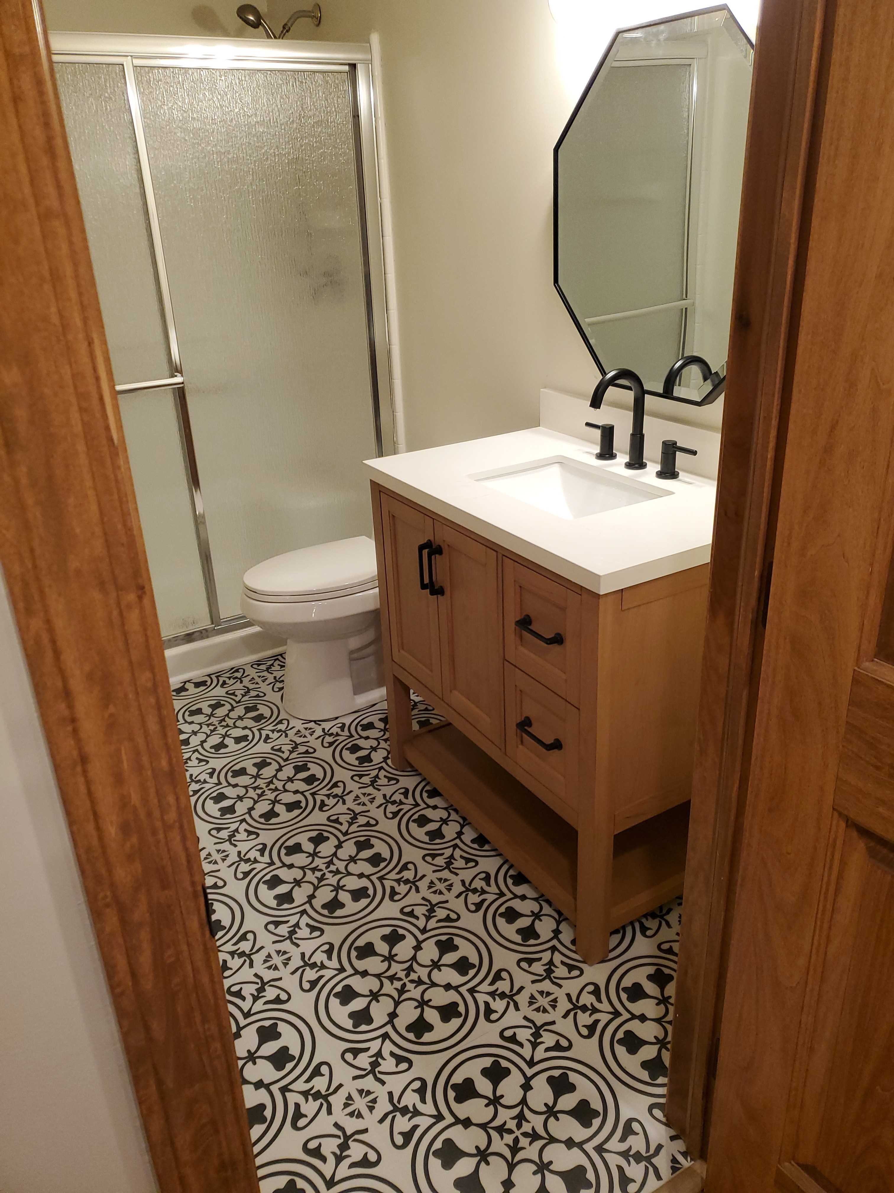 Bathroom with patterned floor and wood vanity renovation.