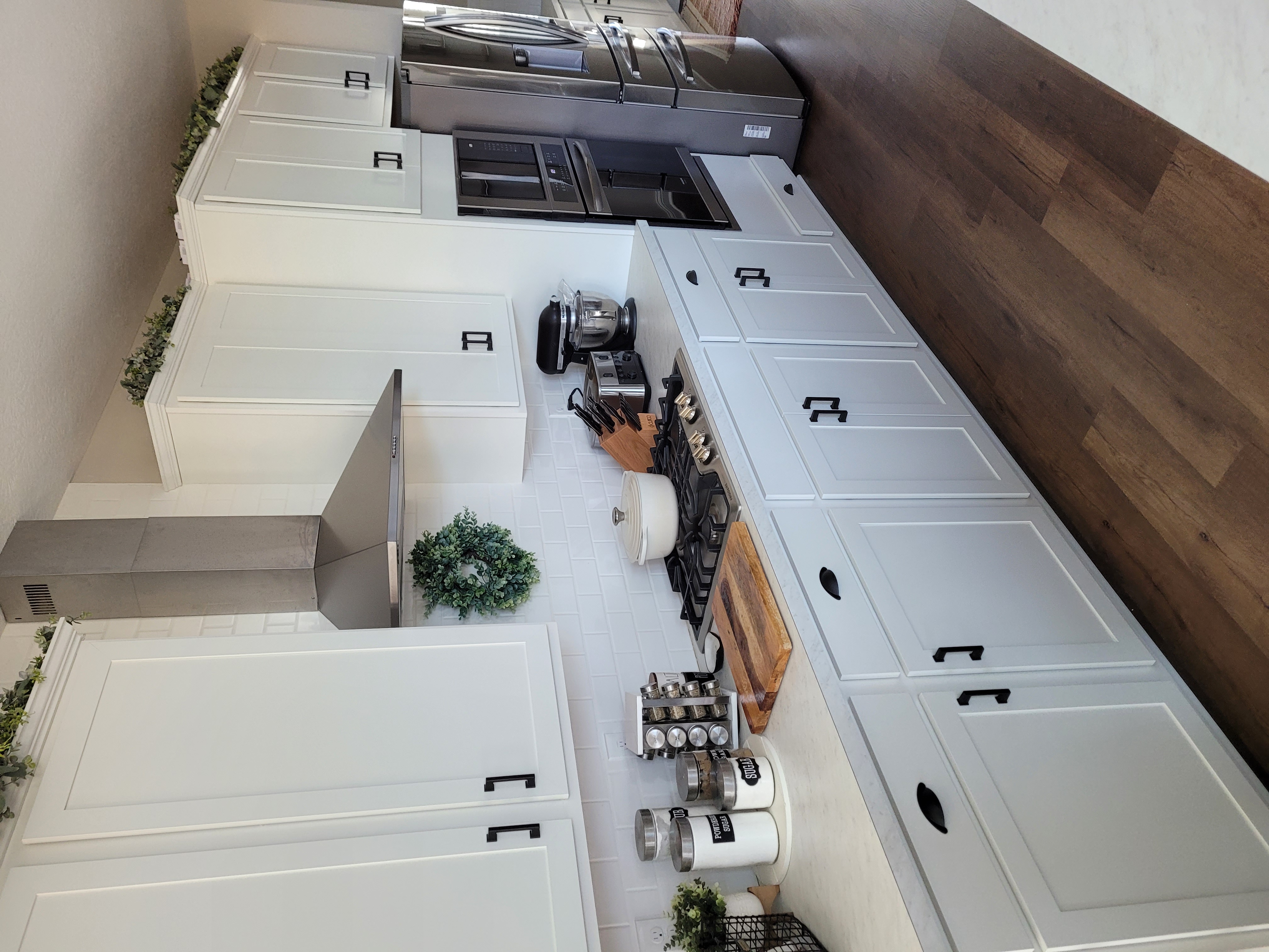 Modern kitchen with white cabinets, stove, and stainless appliances.