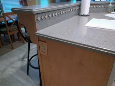 Kitchen counter with a paper towel holder and backsplash tiles.