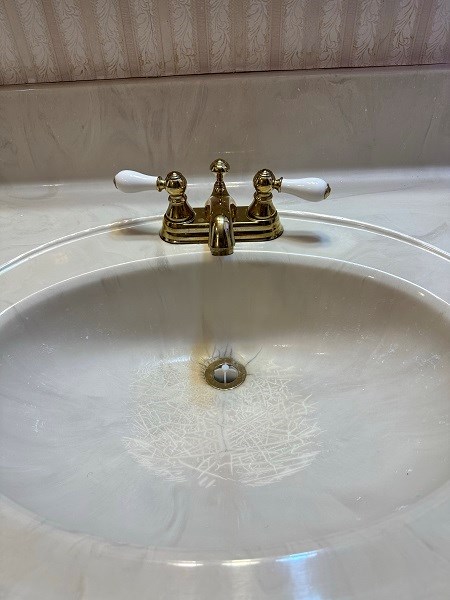 Bathroom sink with gold faucet before renovation.