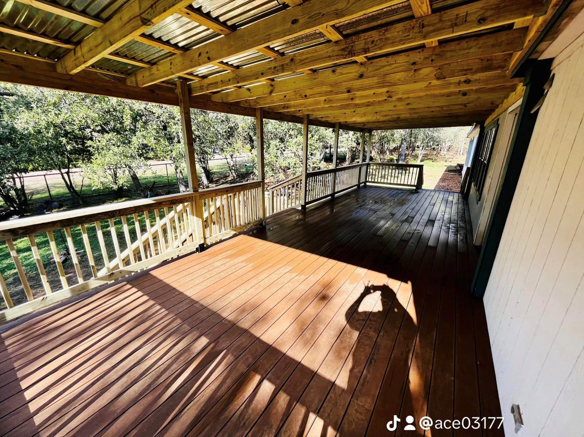 Covered wooden deck with railing and roof shadow.