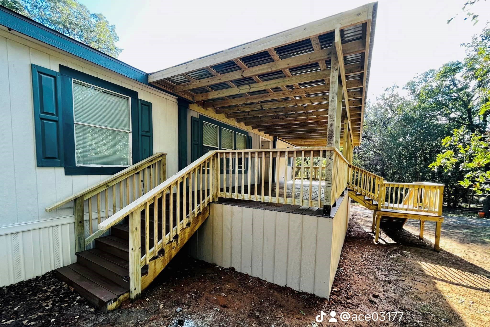 Covered deck and ramp attached to a home in wooded area.