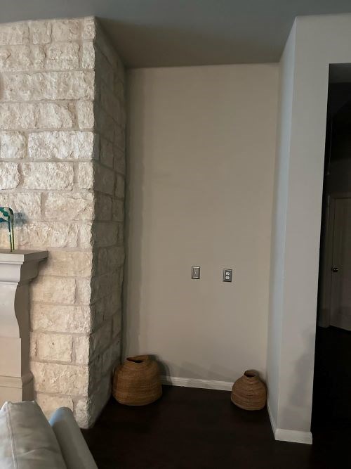 Blank wall with light switches, brick column, and baskets.