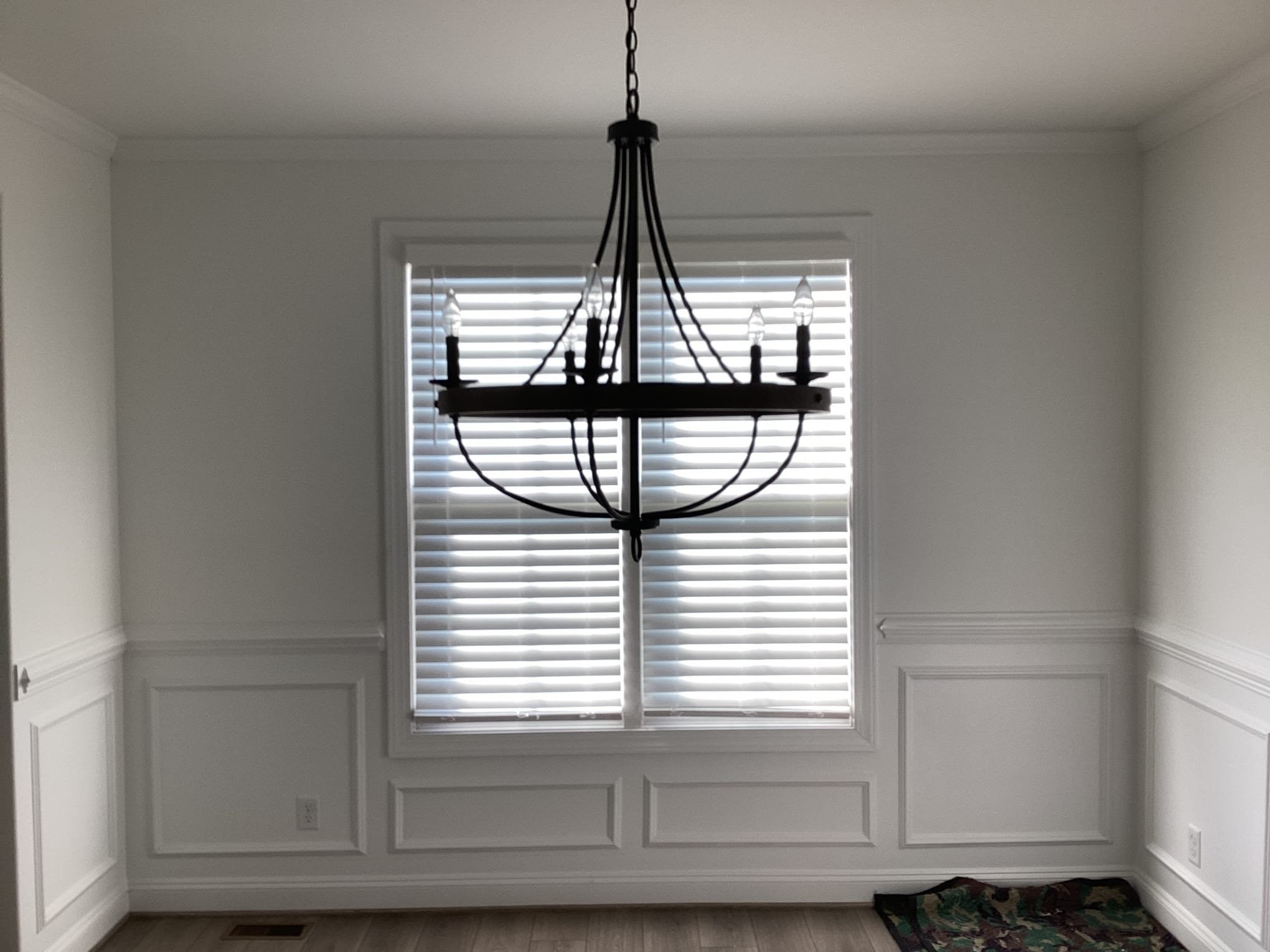 Dining room with chandelier and window blinds.