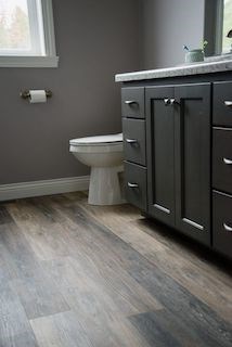 Bathroom with dark cabinets and wood-pattern floor.